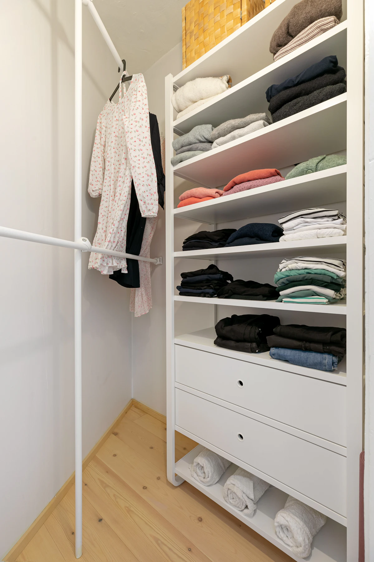 Organized small closet with folded clothes, hanging garments, and open shelves