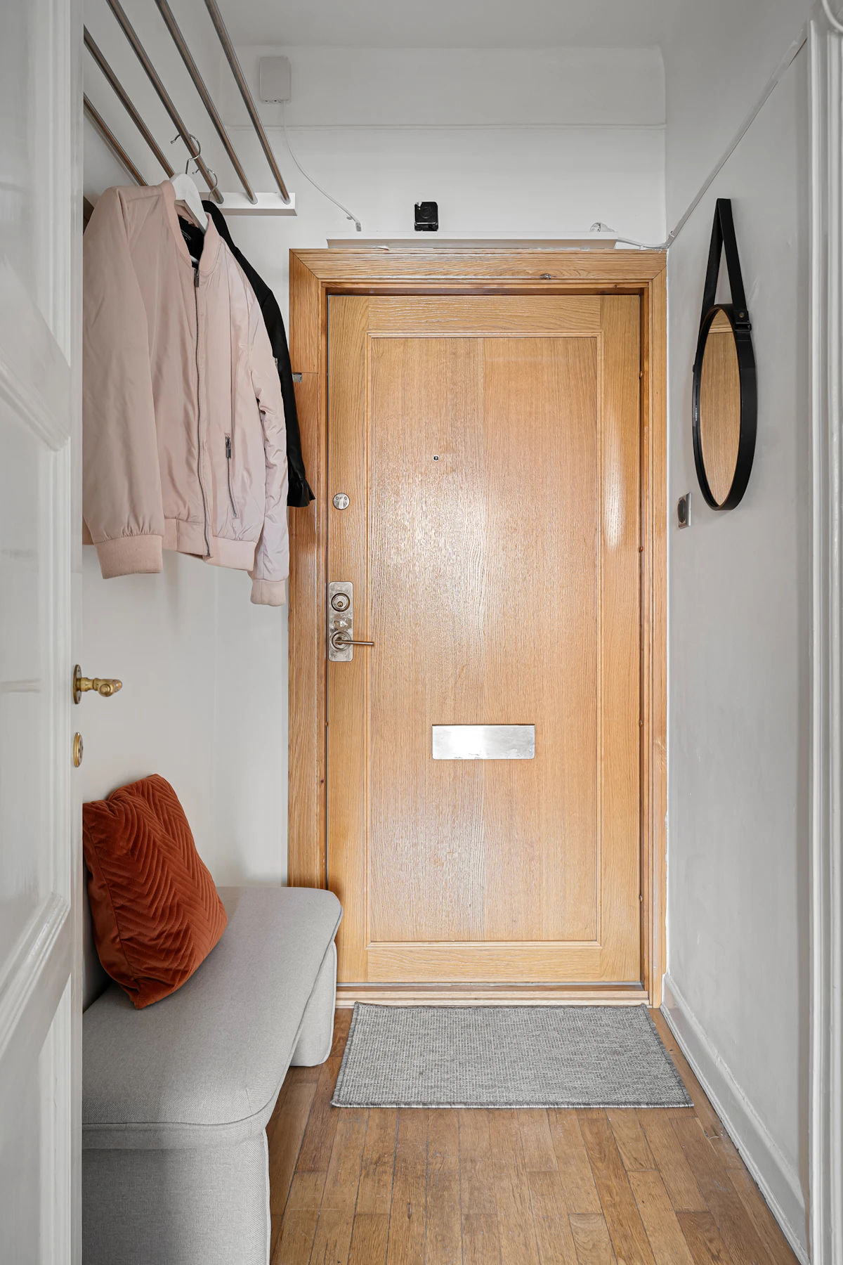 Small entryway with a bench, coat rack, and compact wall storage