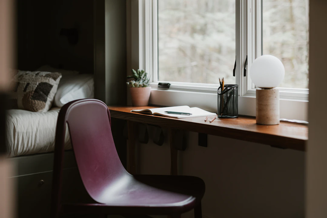 Small bedroom office desk positioned near a bright window