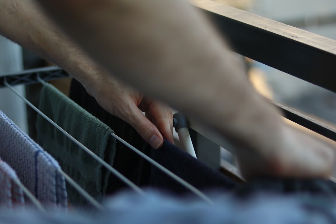Person hanging clothes on an indoor drying rack with space between garments