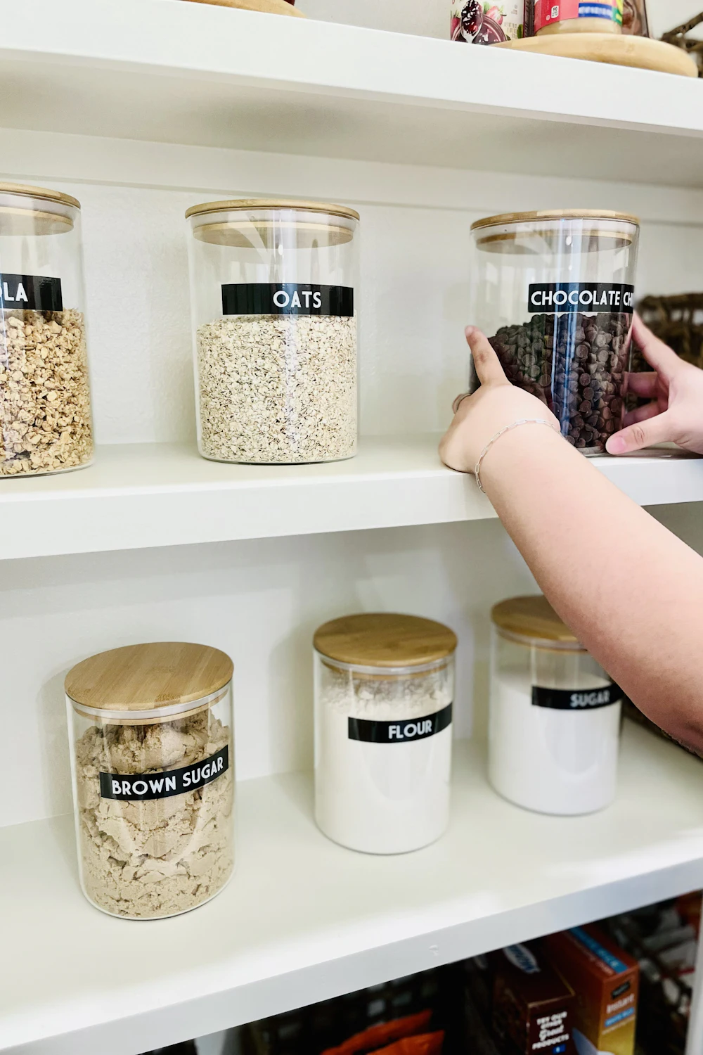 Organized pantry shelf with labeled glass canisters for dry goods