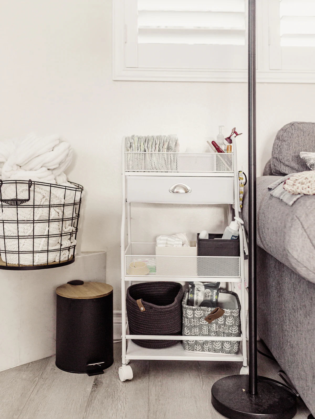 White three-tier rolling cart holding neatly arranged supplies in baskets