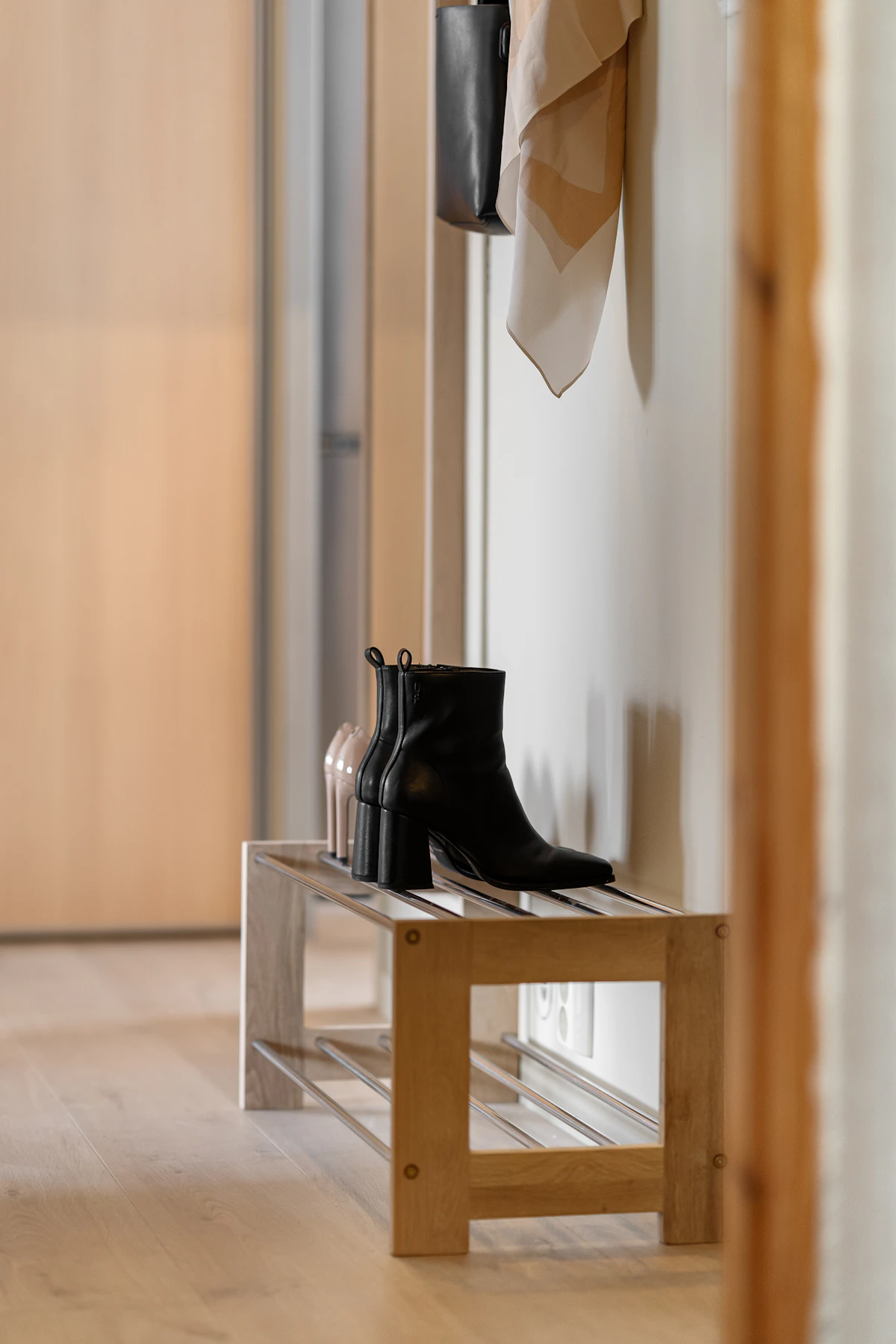 Black boots beside a compact wooden bench in an entryway