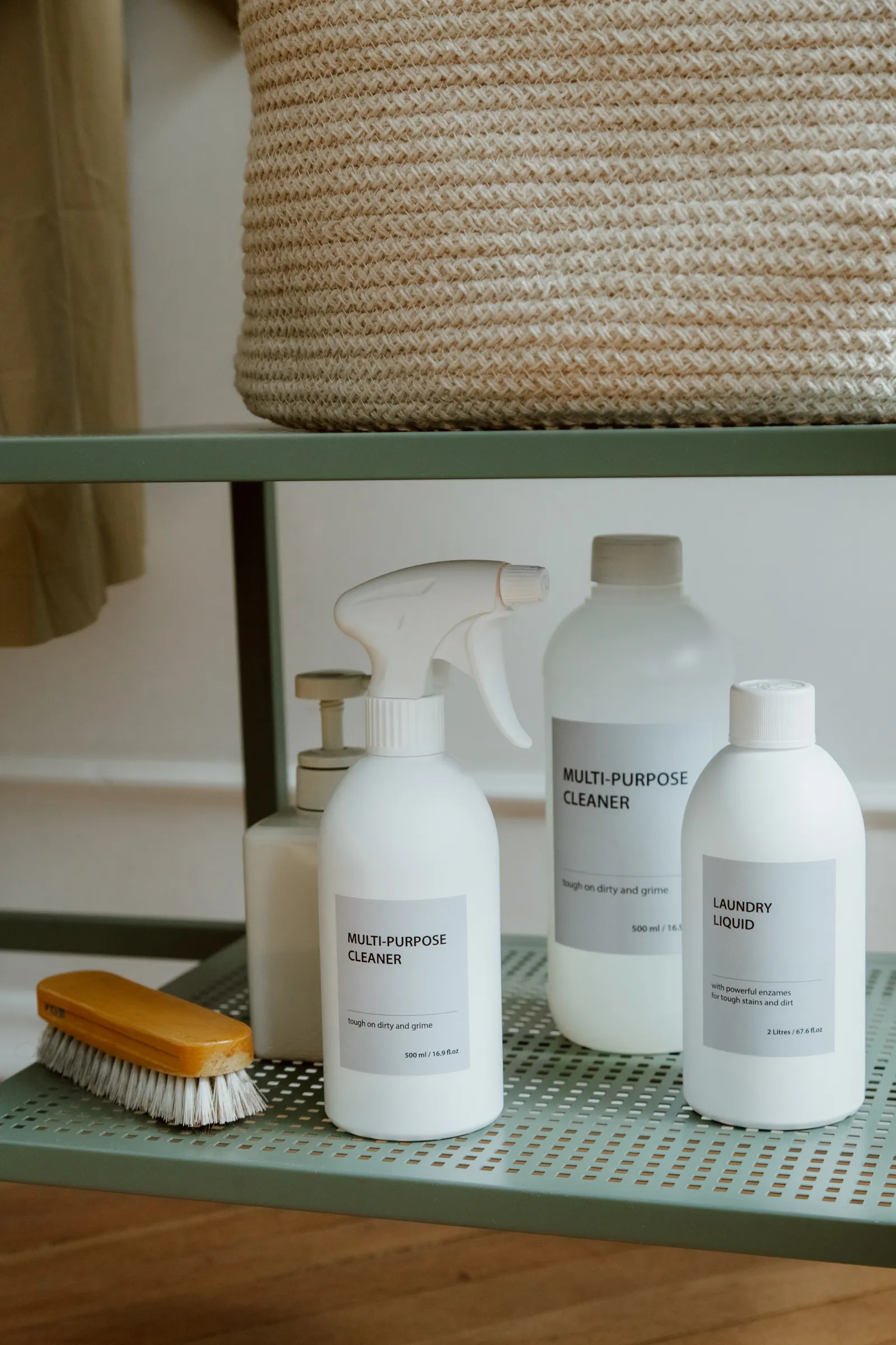 Bottles, brushes, cloths and cleaning supplies arranged on an open metal shelf
