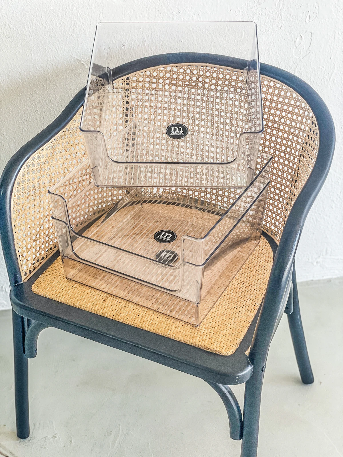 Two clear plastic storage organizers stacked on a woven chair