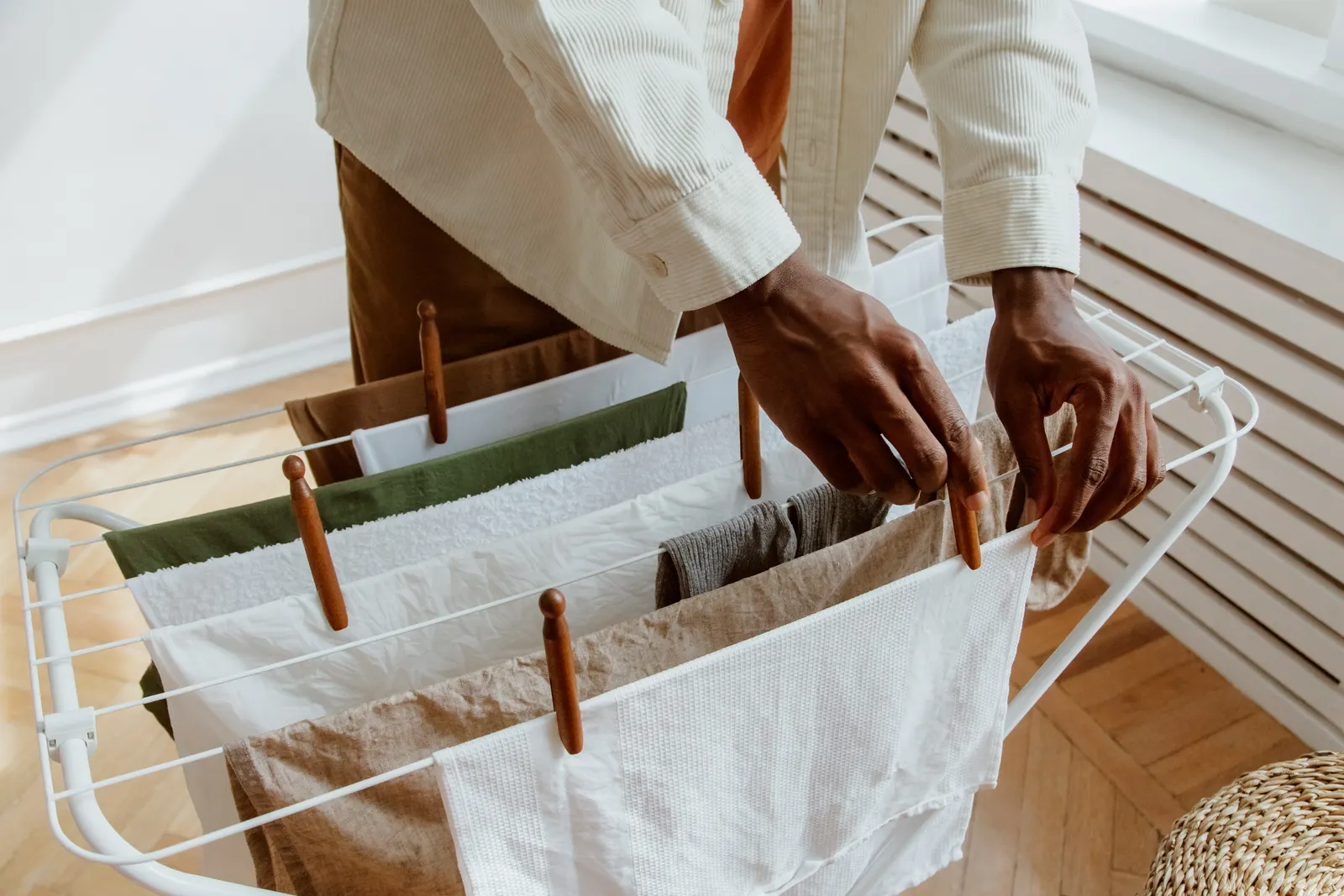 Person clipping a garment to an indoor drying rack with space between items