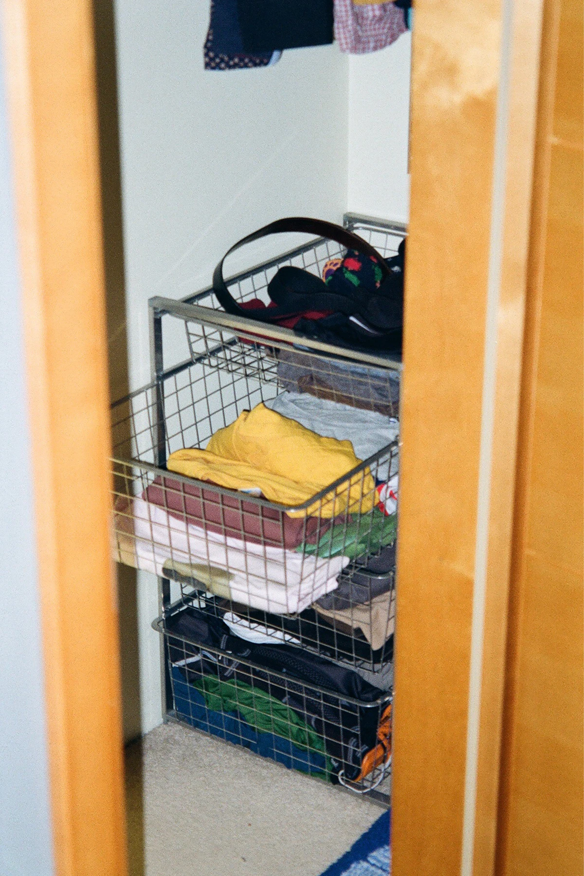 Wire baskets in a closet holding separate stacks of folded clothes