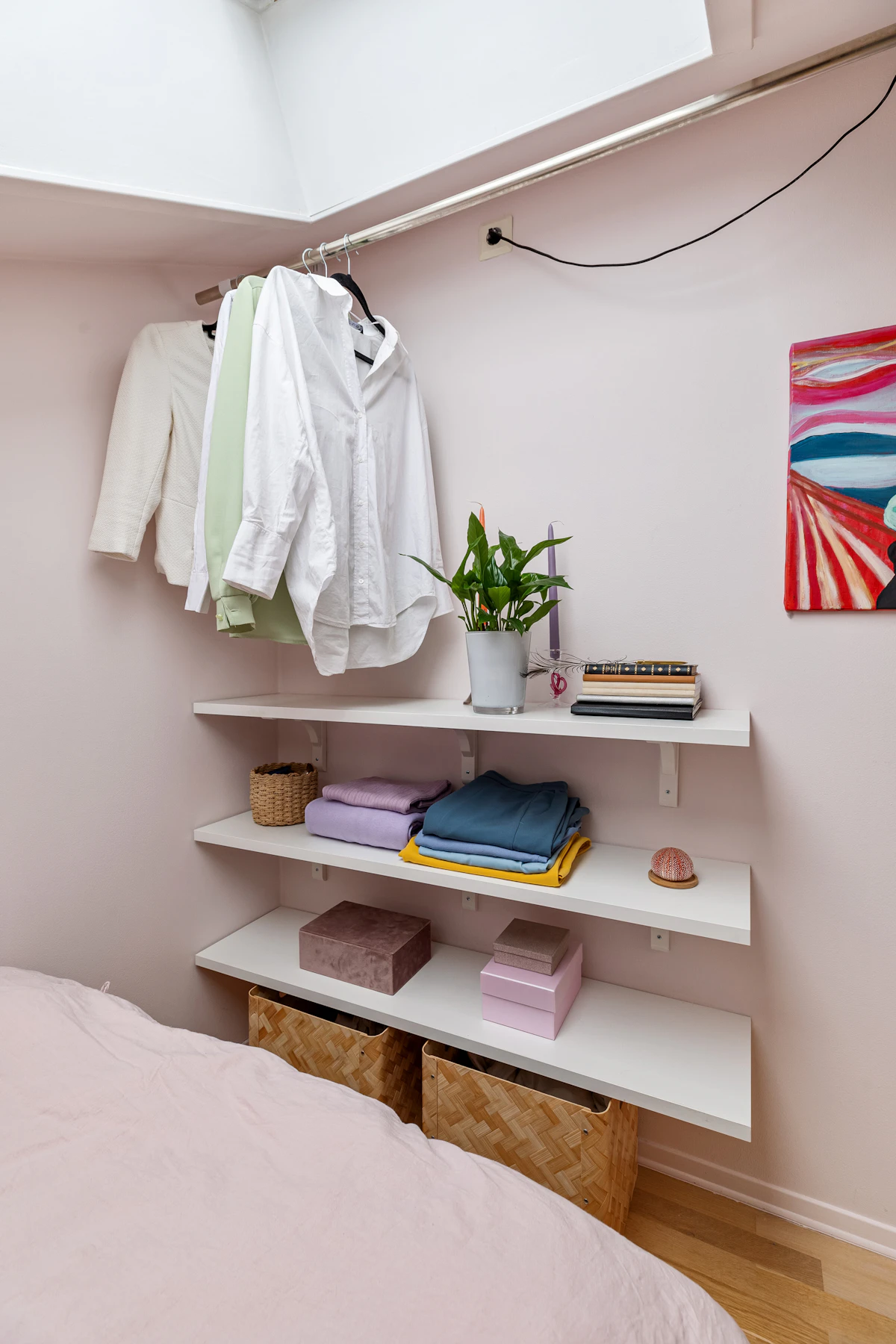 Small bedroom with open wall shelves holding folded clothes and baskets