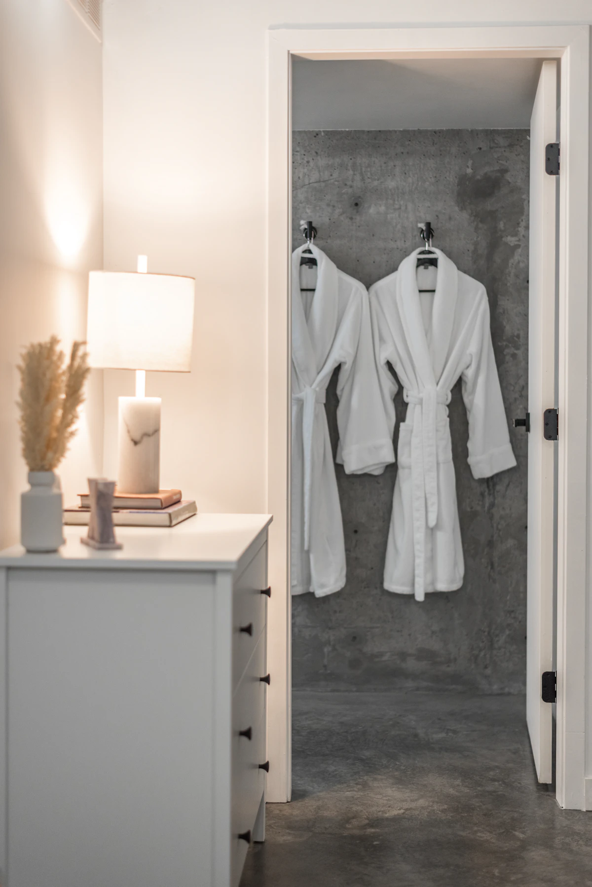 White robes hanging on hooks beside a bedroom doorway