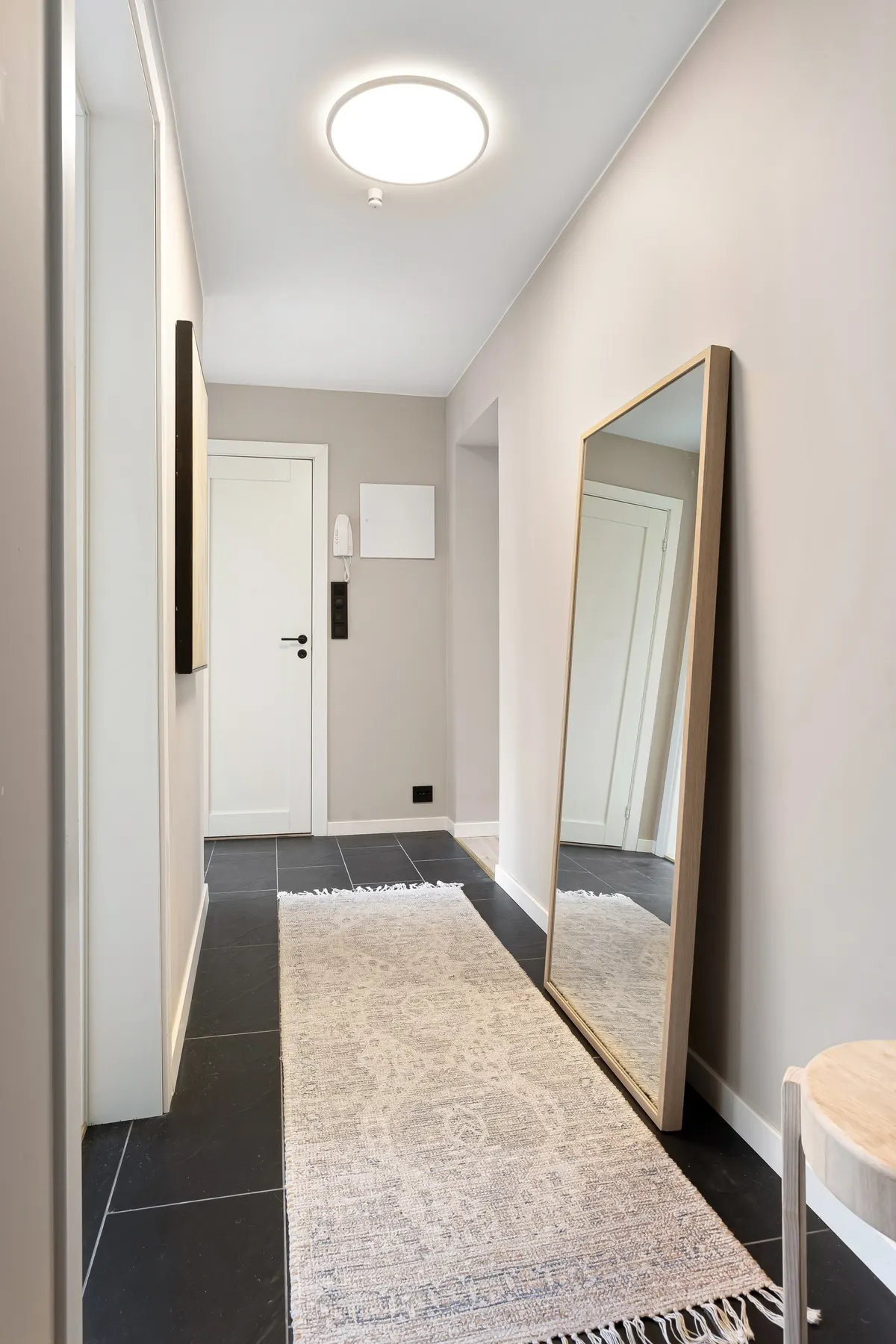 Bright apartment hallway with a long runner rug and large mirror