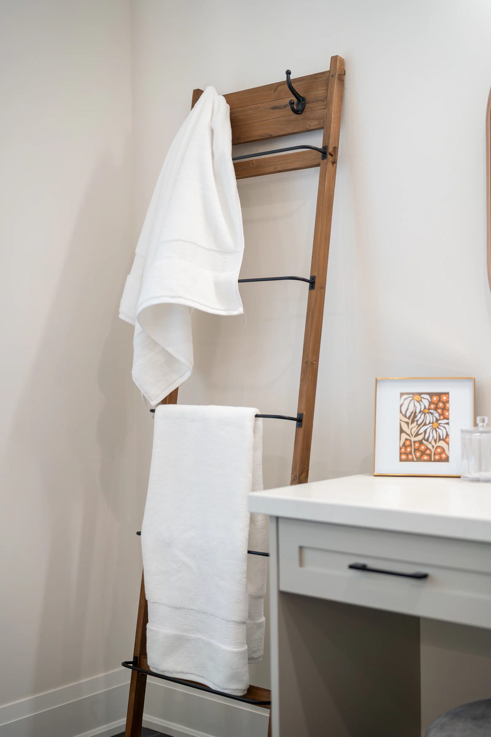 Wooden ladder rack holding folded white towels in a bathroom