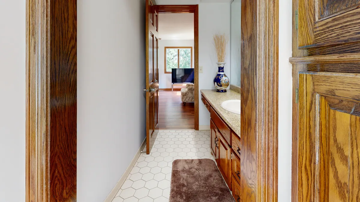 Narrow hallway opening into a living room with natural wood details
