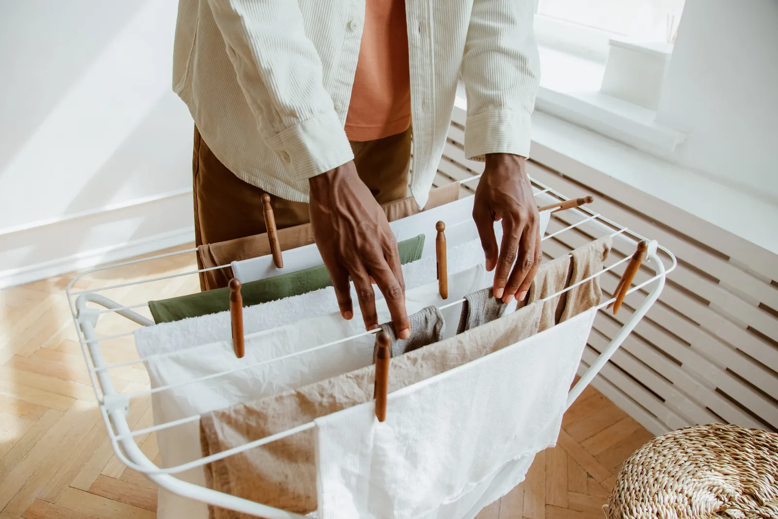 Person hanging freshly washed clothes to air-dry in a bright room