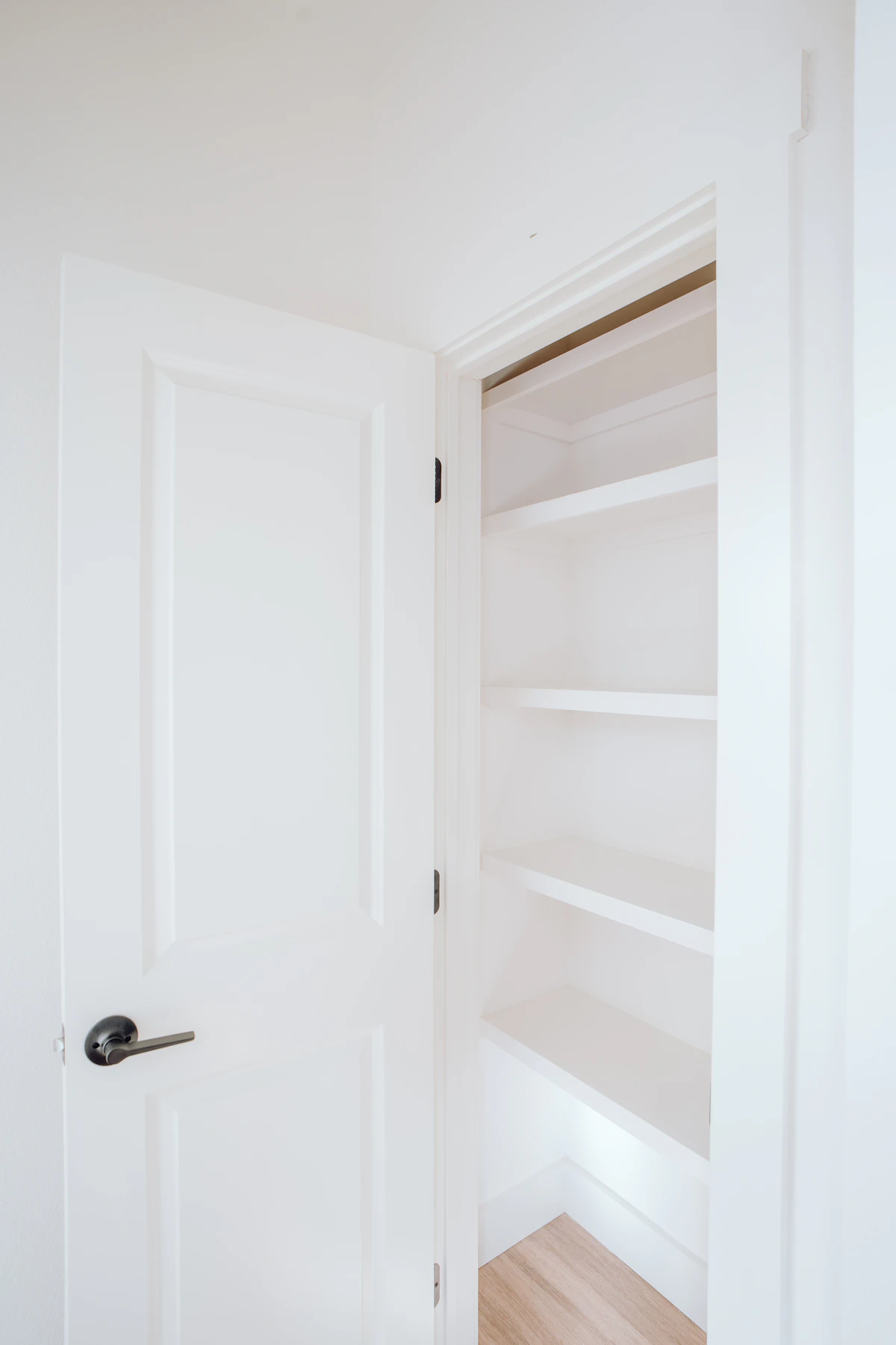 Open white bedroom door beside built-in closet shelves