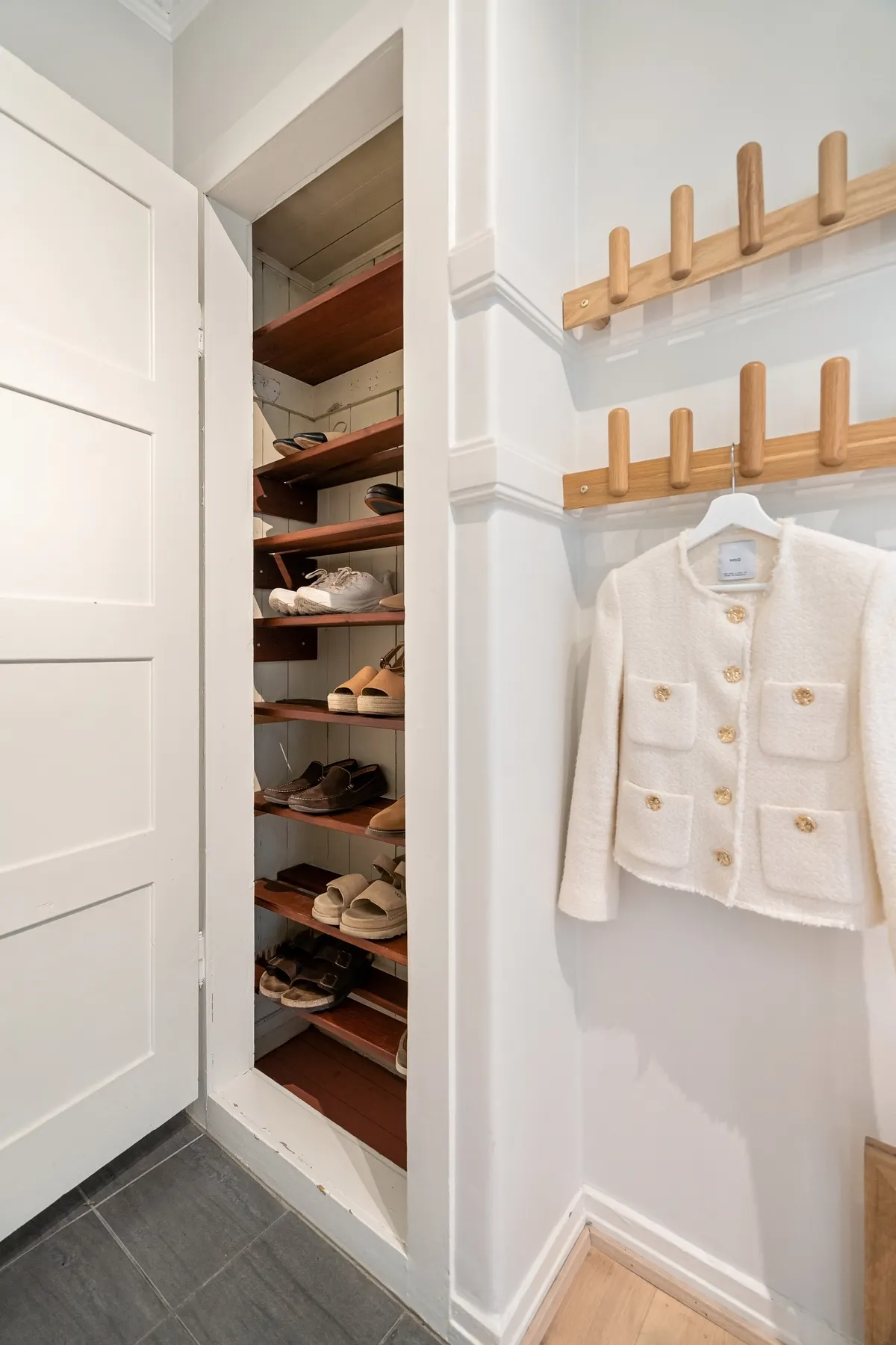 Open apartment wardrobe with shoes stored on lower shelves
