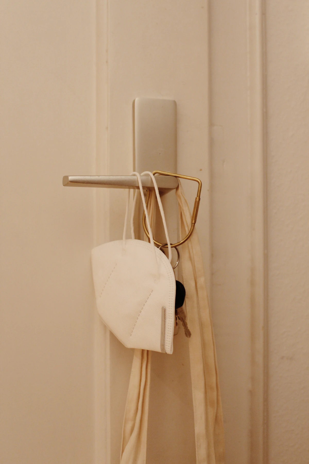 Small over-door hook holding a lightweight face covering