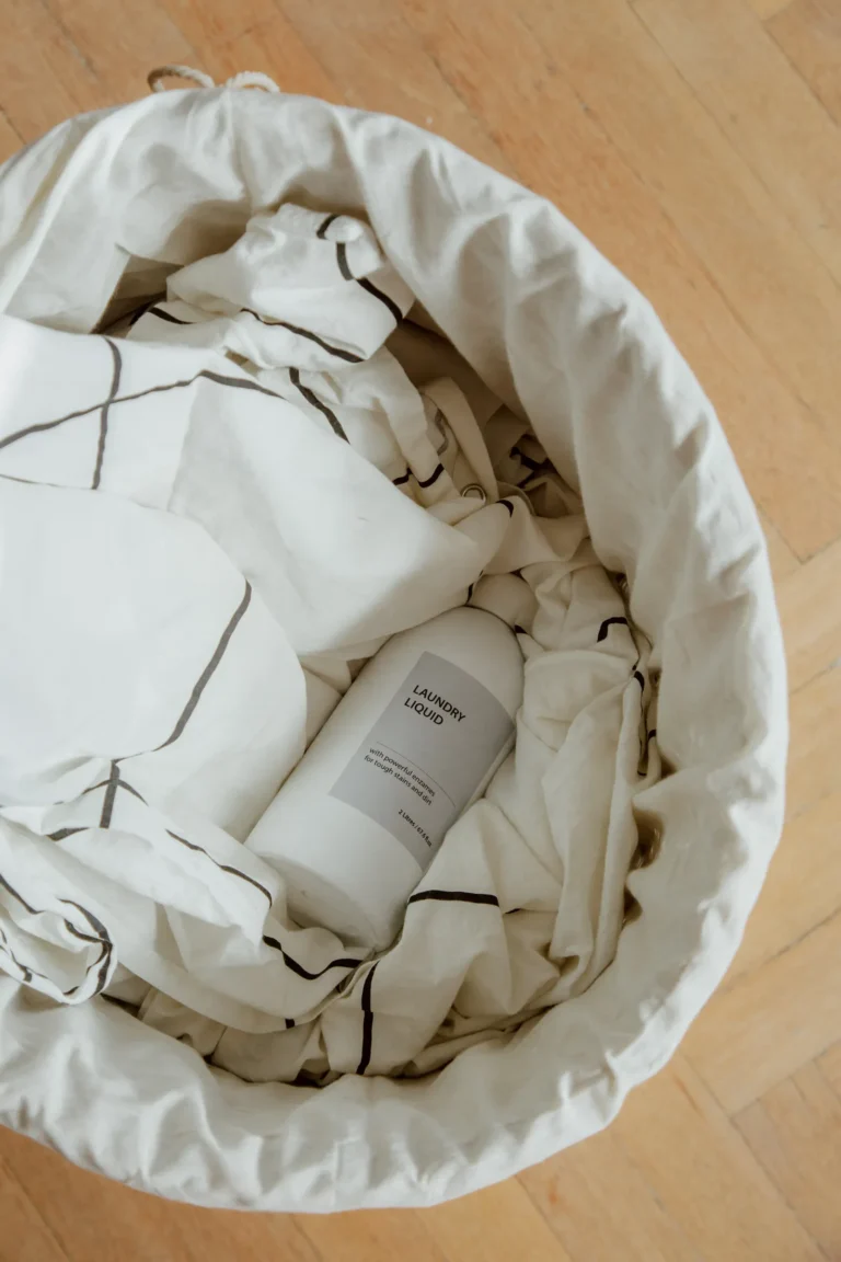 Handled laundry basket with clothes and detergent, showing where to store laundry supplies for a shared laundry trip