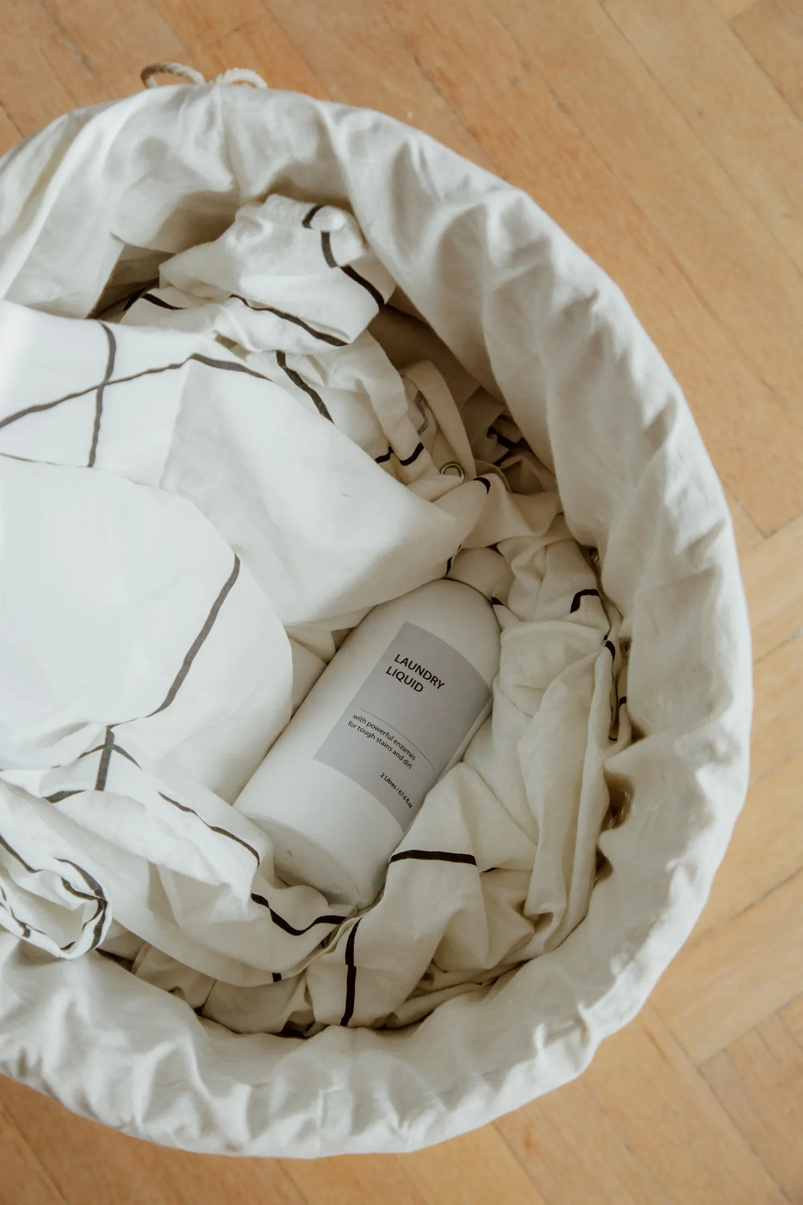 Handled laundry basket with clothes and detergent, showing where to store laundry supplies for a shared laundry trip