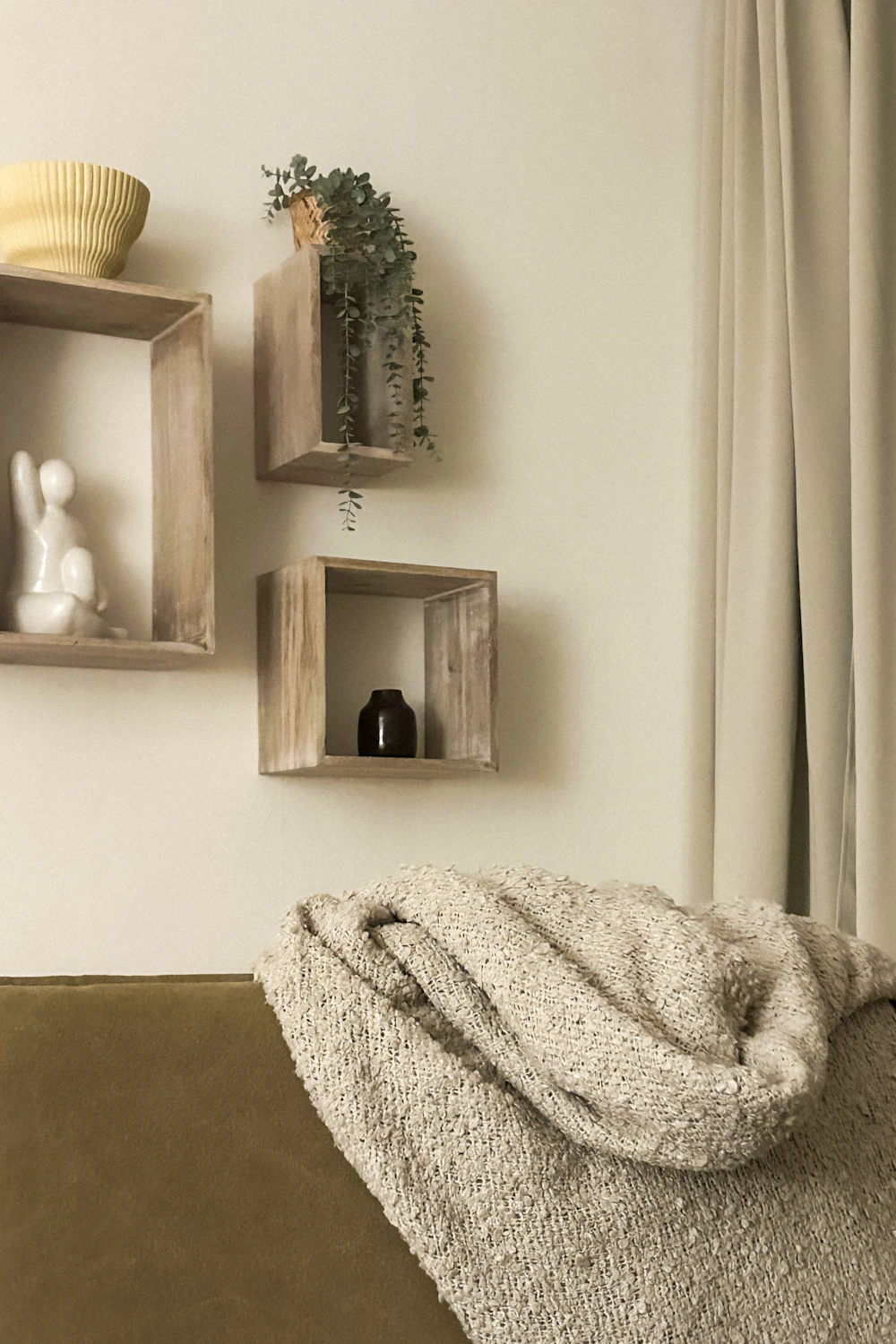 Renter-friendly wall storage shelves above a sofa in a compact apartment