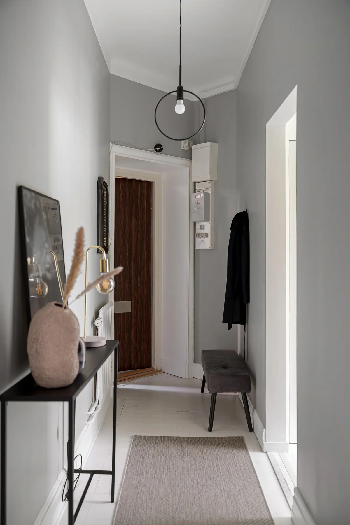 Narrow apartment hall with a slim console, bench and runner rug