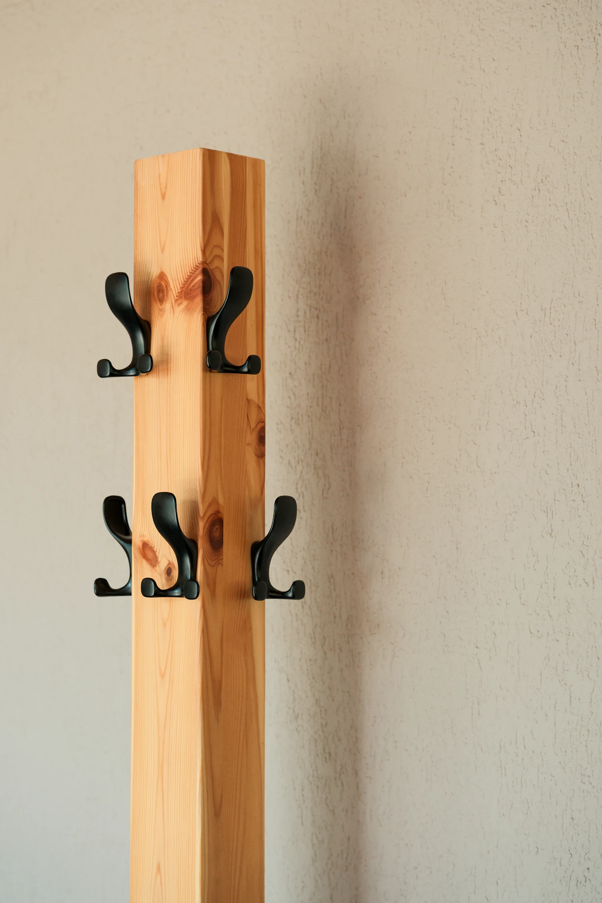 Wooden wall-mounted coat rack with black hooks